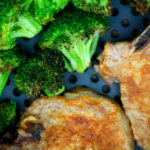 cooked broccoli and pork chops in an air fryer pan