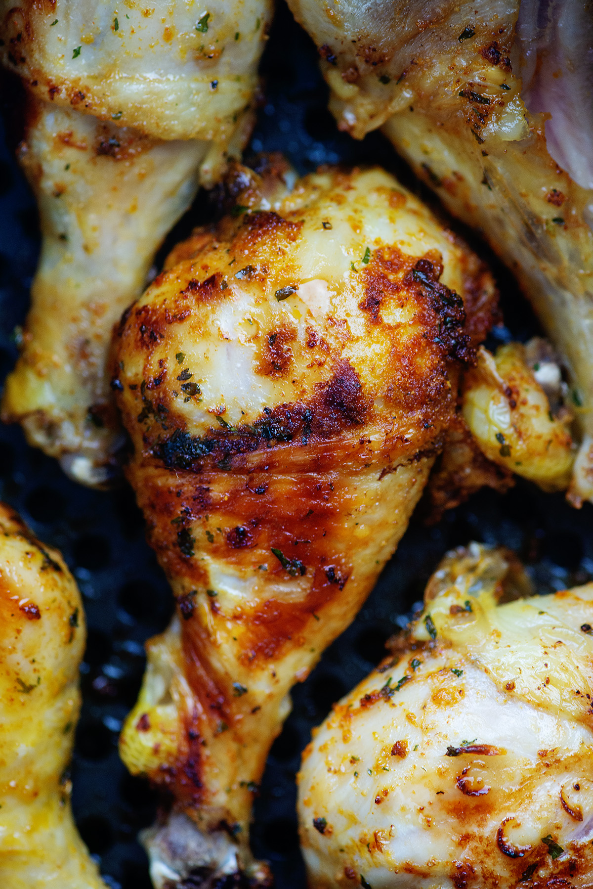 A close up of chicken drumsticks close together in a an air fryer pan.