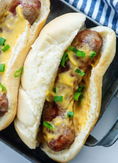 Overhead view of a cheesy brat topped with green onions.