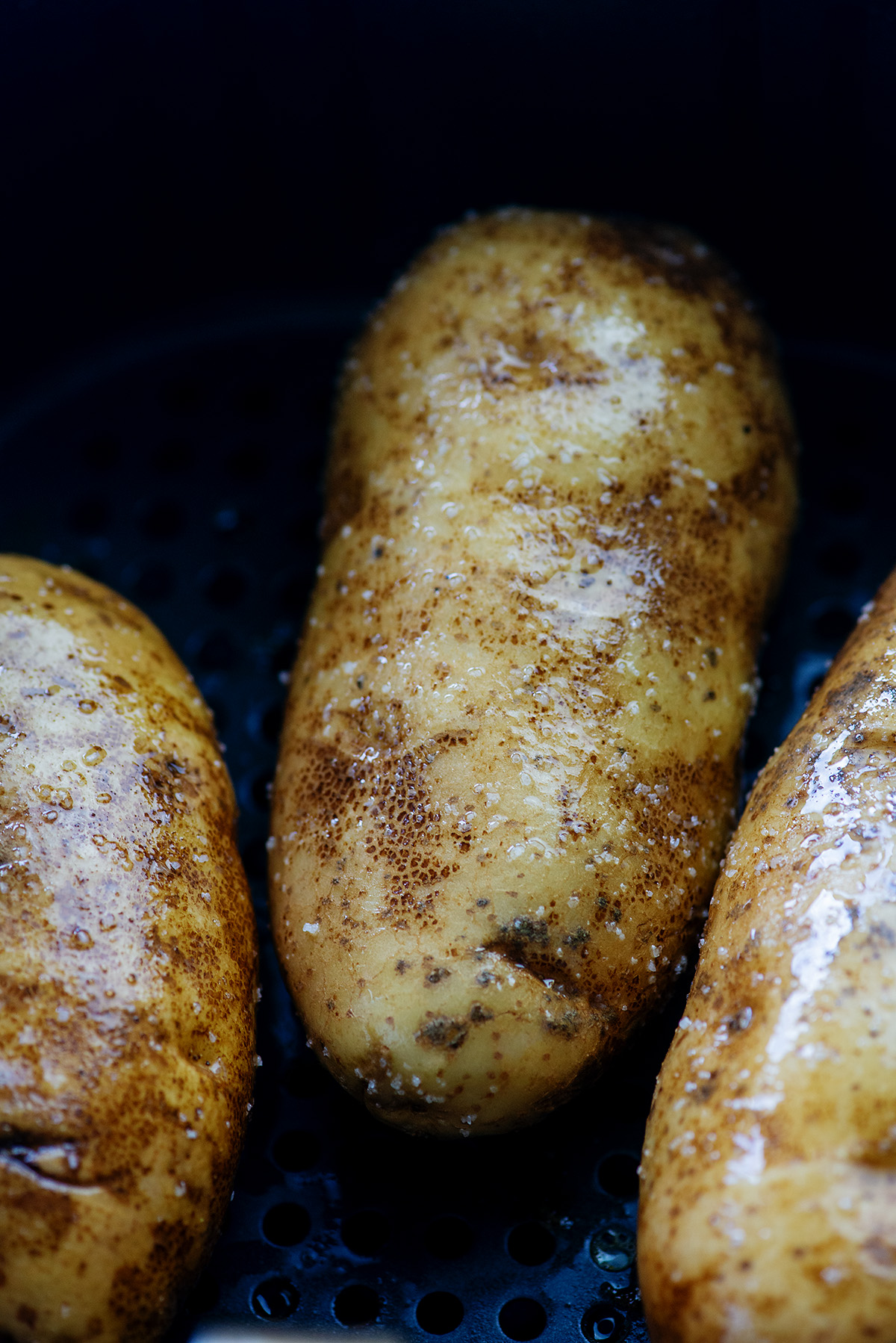 A close up of potatoes sitting in an air fryer.