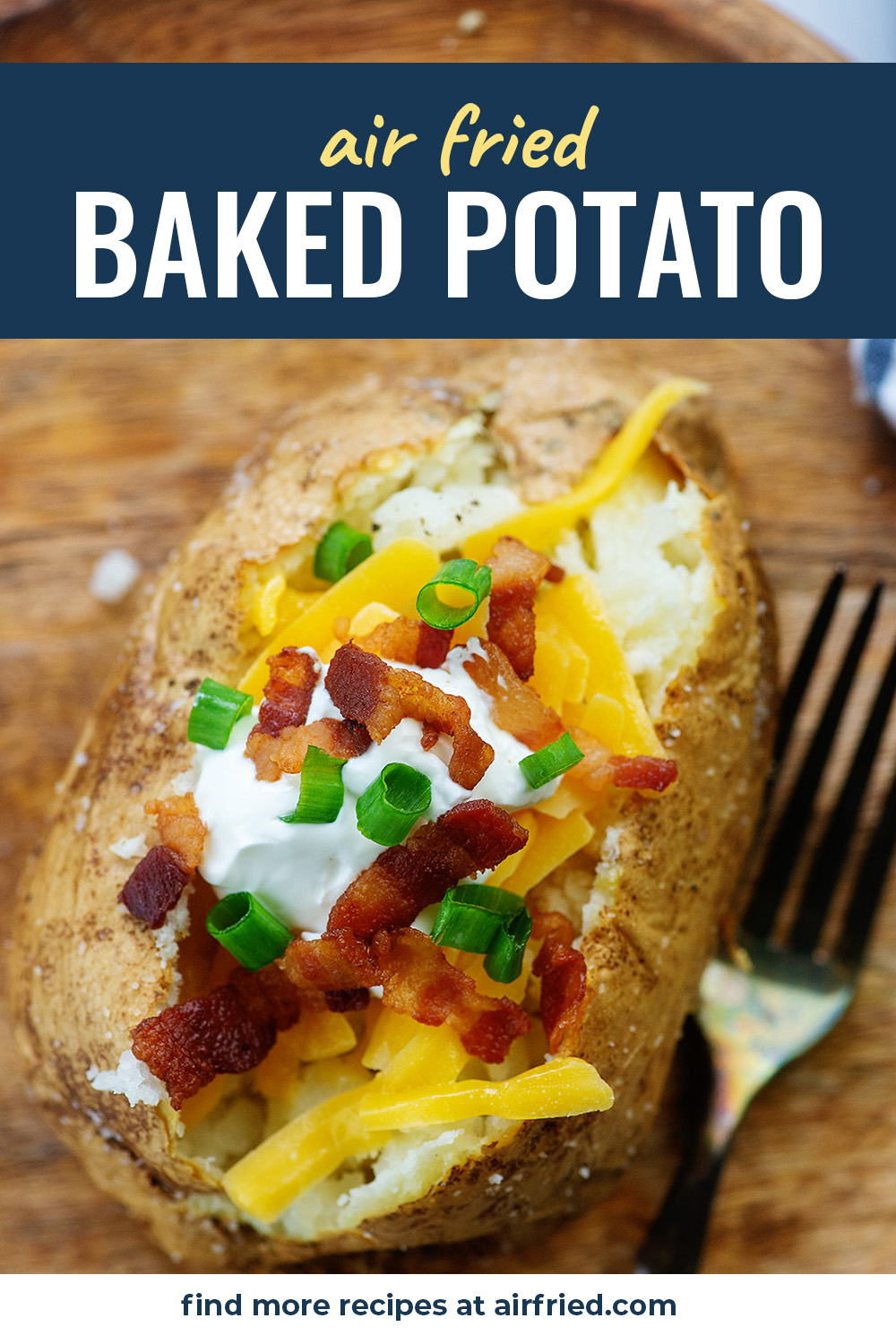 An overhead view of a loaded baked potato on a wooden cutting board.
