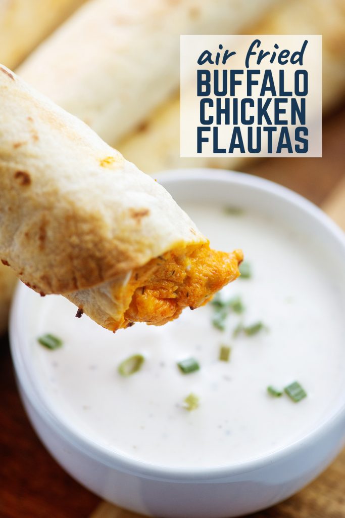 Flauta held up to the camera above a bowl of ranch dressing.
