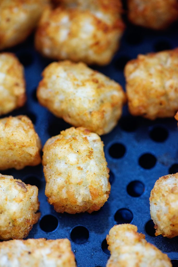 A close up of cooked tater tots in an air fryer