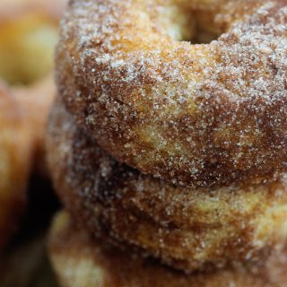 A stack of three biscuit donuts covered in cinnamon and sugar