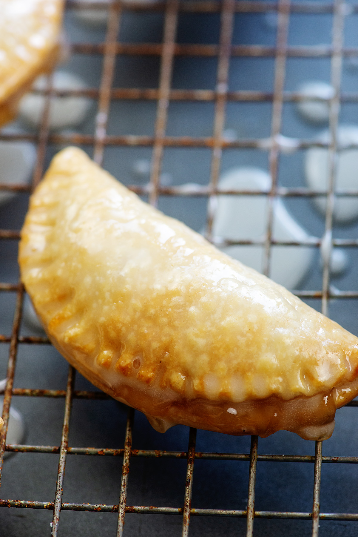 A close up o f a vanilla glazed apple pie on a cooling rack.