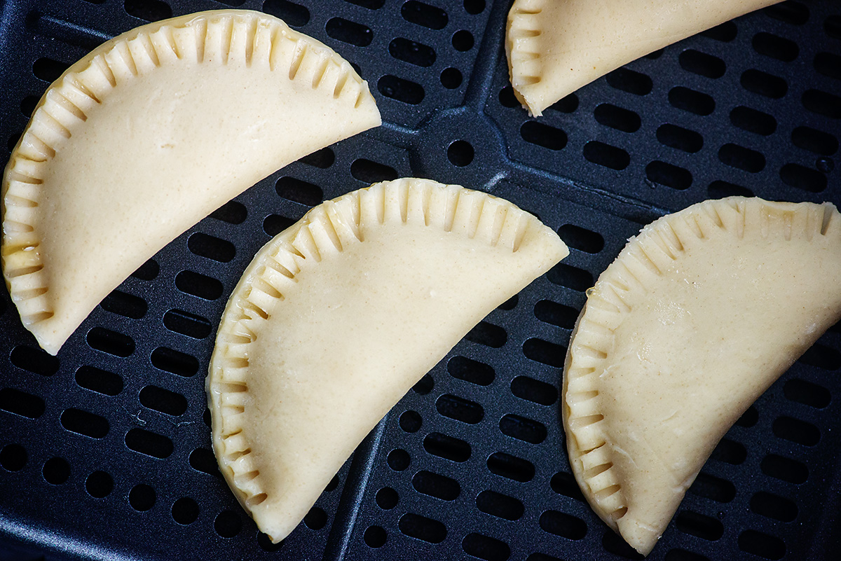 Raw mini apple pies in air fryer basket