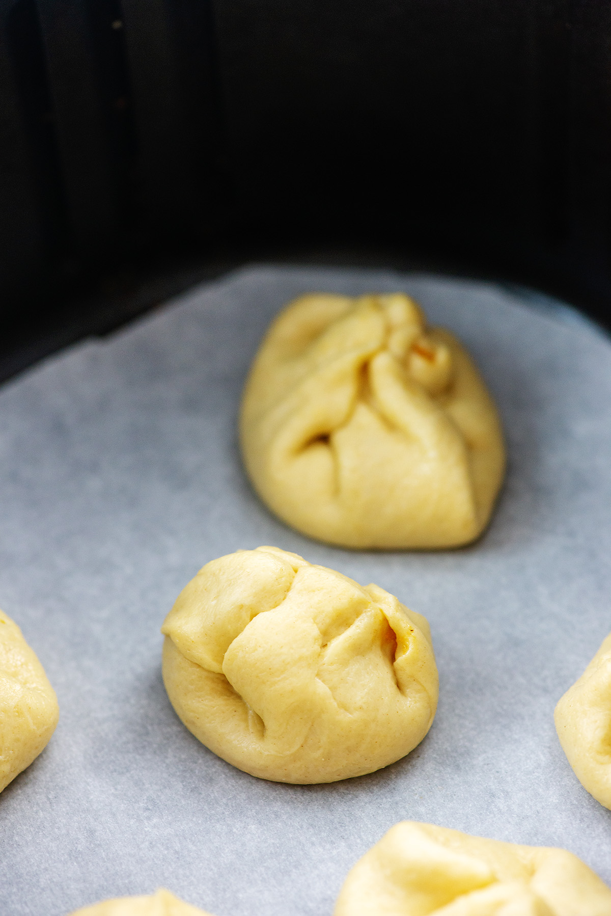 Pumpkin bomb dough balls on parchment paper in an air fryer basket