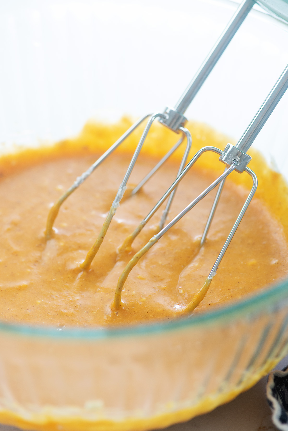 Pumpkin batter being beat in a glass bowl