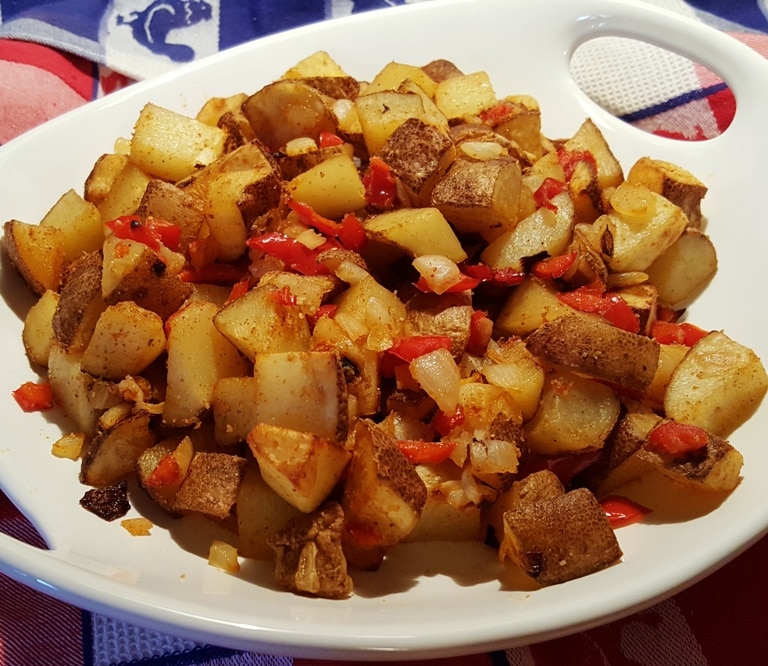 Diced potatoes seasoned and piled on a white plate.