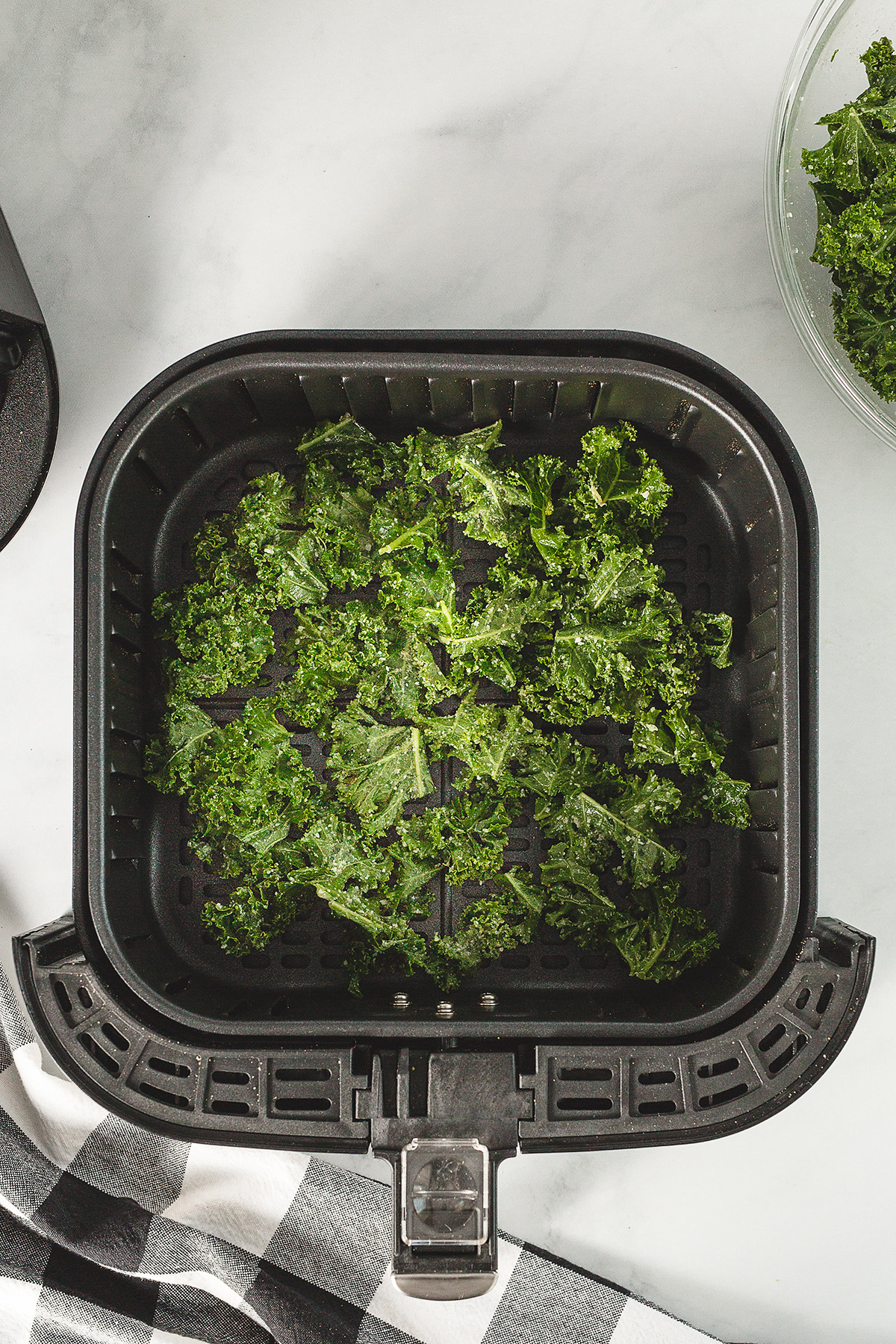 Overhead view of kale chips in an air fryer basket
