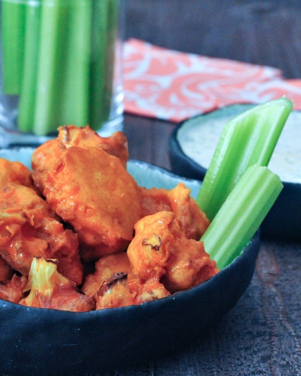 Chicken wings and celery sticks in a bowl on a table.
