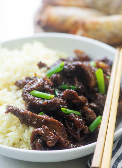 Mongolian beef on a white plate with chopsticks