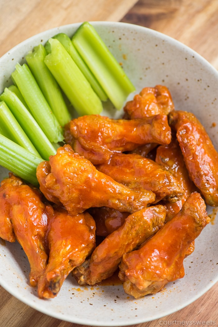 Overhead view of buffalo wings and celery on a plate.