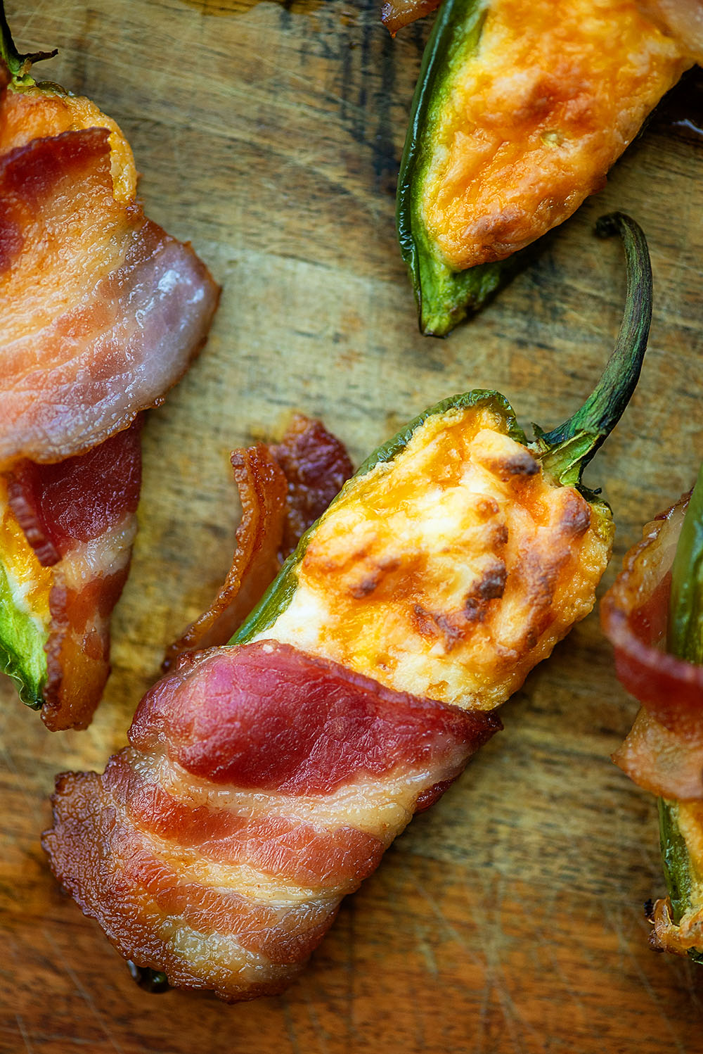 Bacon wrapped jalepenos on a wooden cutting board