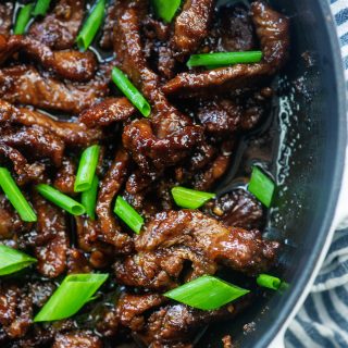Overhead view of mongolian beef in a black bowl.