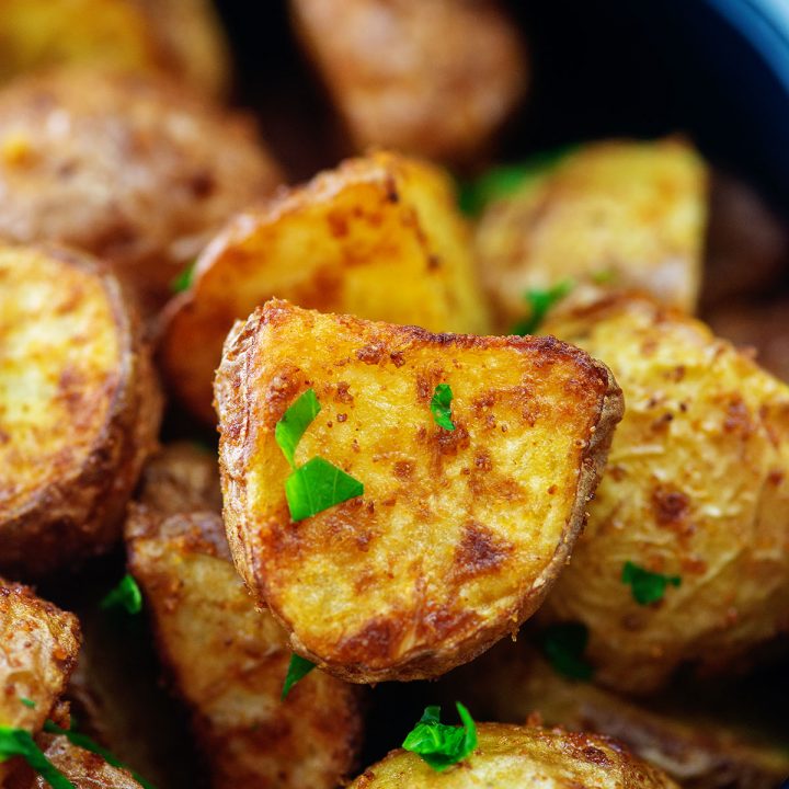 A close up of garlic butter potatoes in a black bowl.