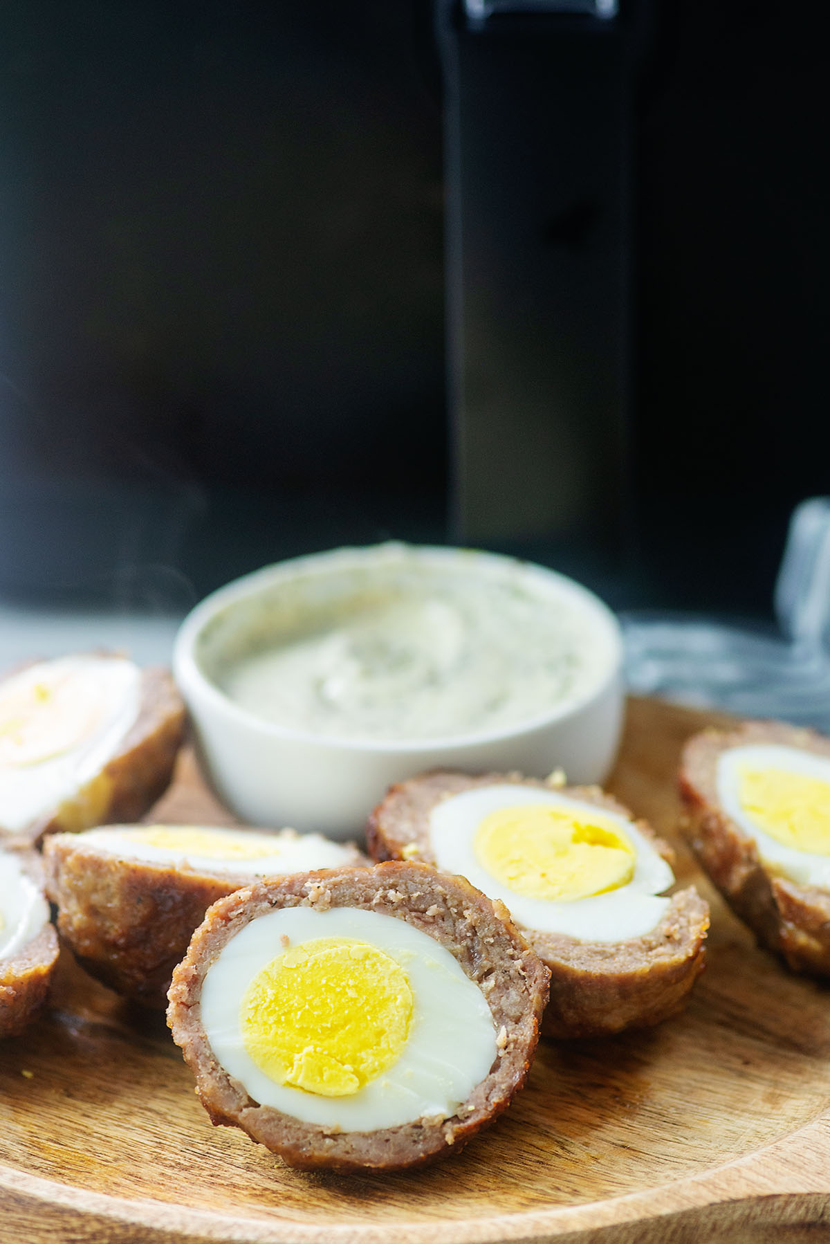 halved eggs with dip on wooden cutting board.