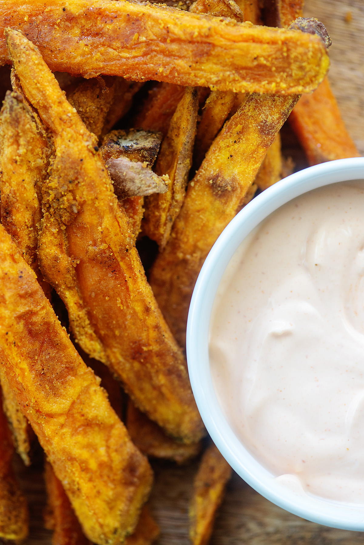 Overhead view of sweet potato fries next to a cup of dipping sauce.