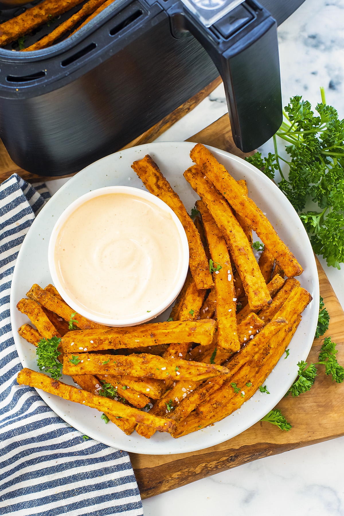 Overhead view of homemade sweet potato fries on plate with dip.