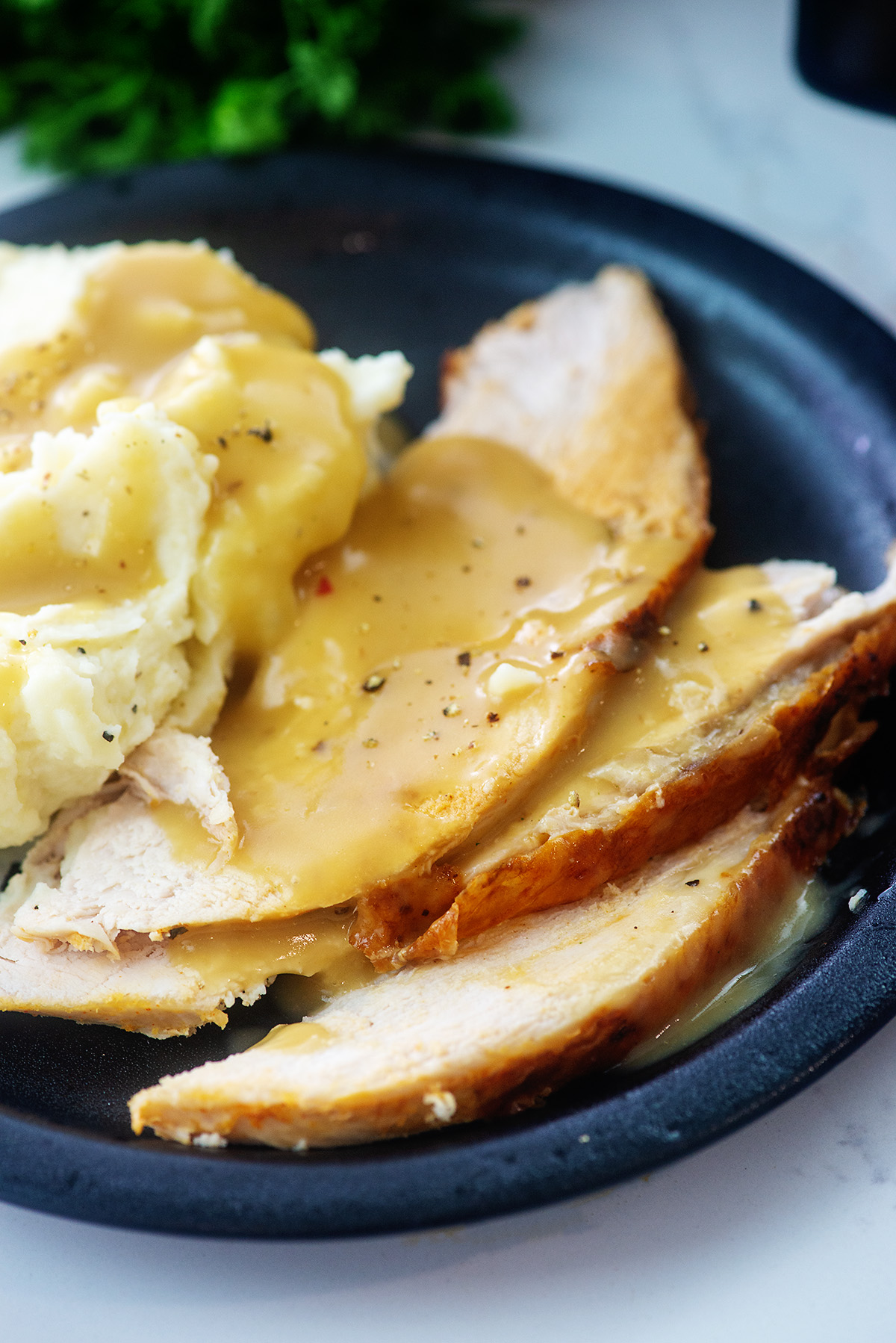 A close up of mashed potatoes and turkey covered in gravy.