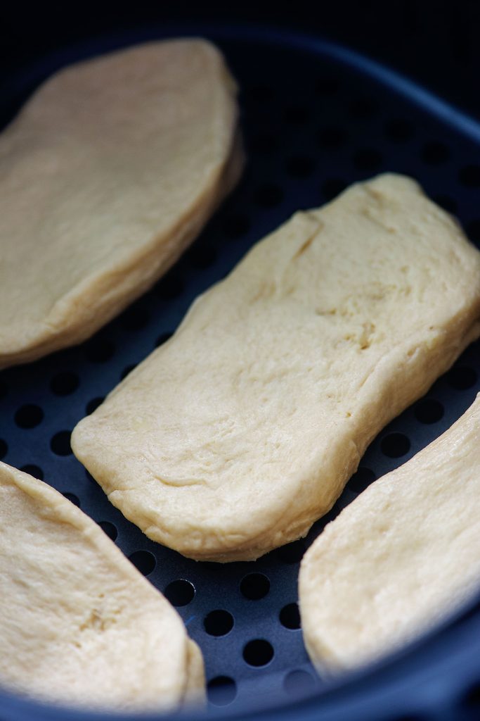 raw biscuits in a rectangle shape in an air fryer basket.