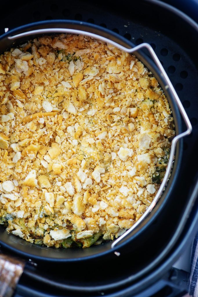 Top down view of broccoli casserole topped with crackers in an air fryer basket.