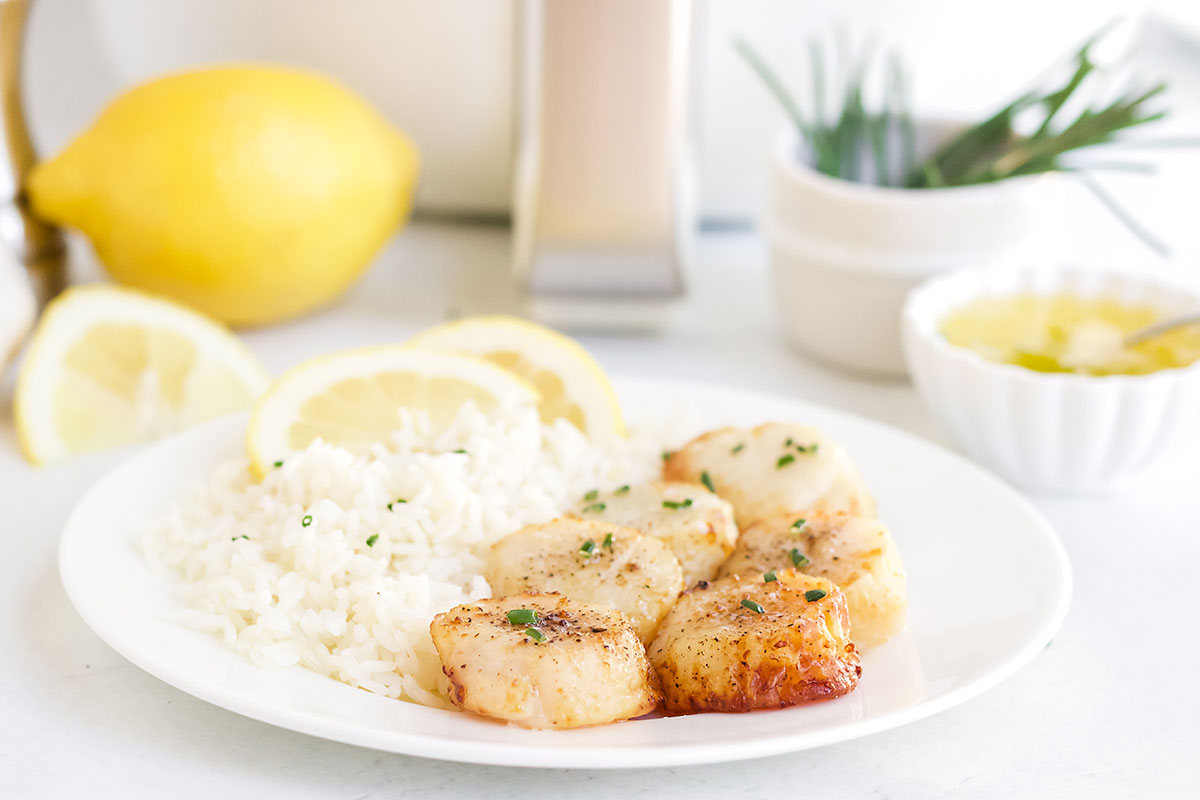 Sliced lemons on a plate with rice and scallops