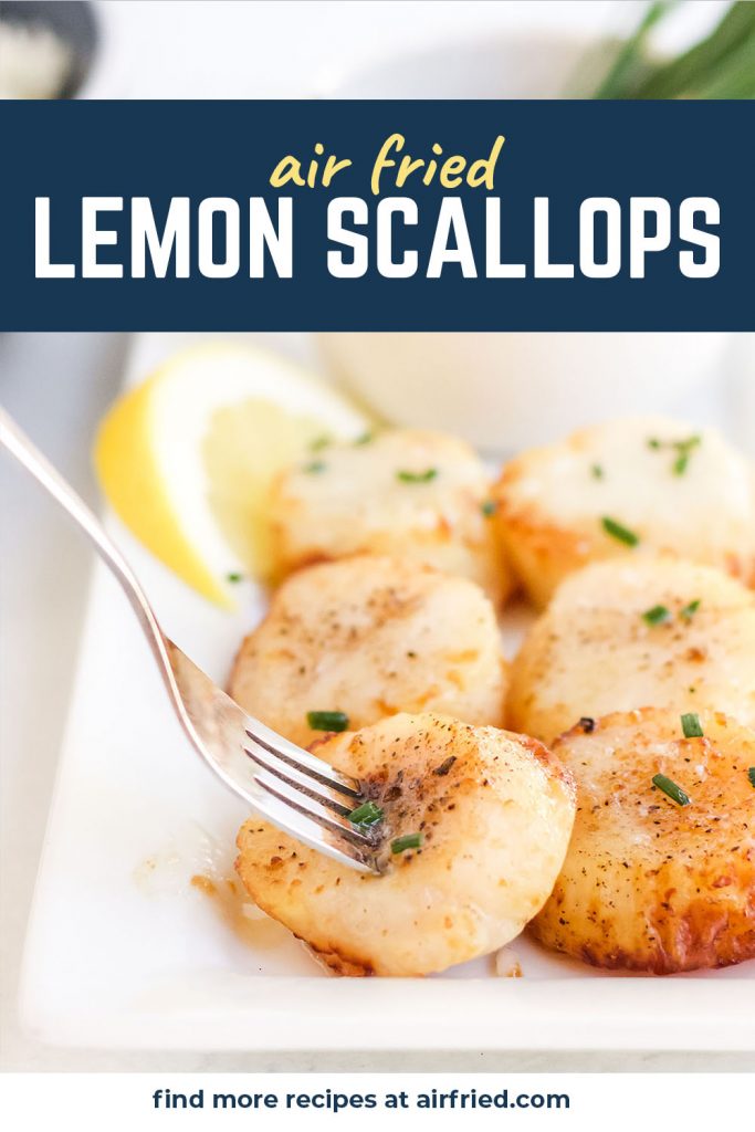 A fork stabbed into one scallop on a plate of scallops