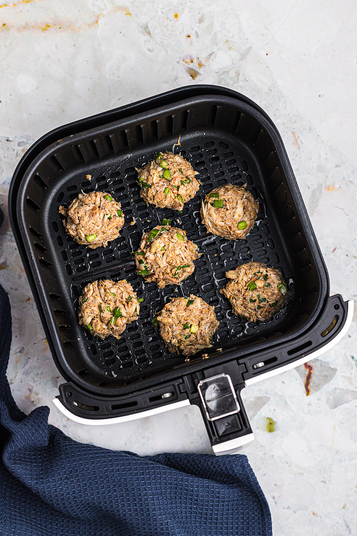 Overhead view of crab cakes in an air fryer basket