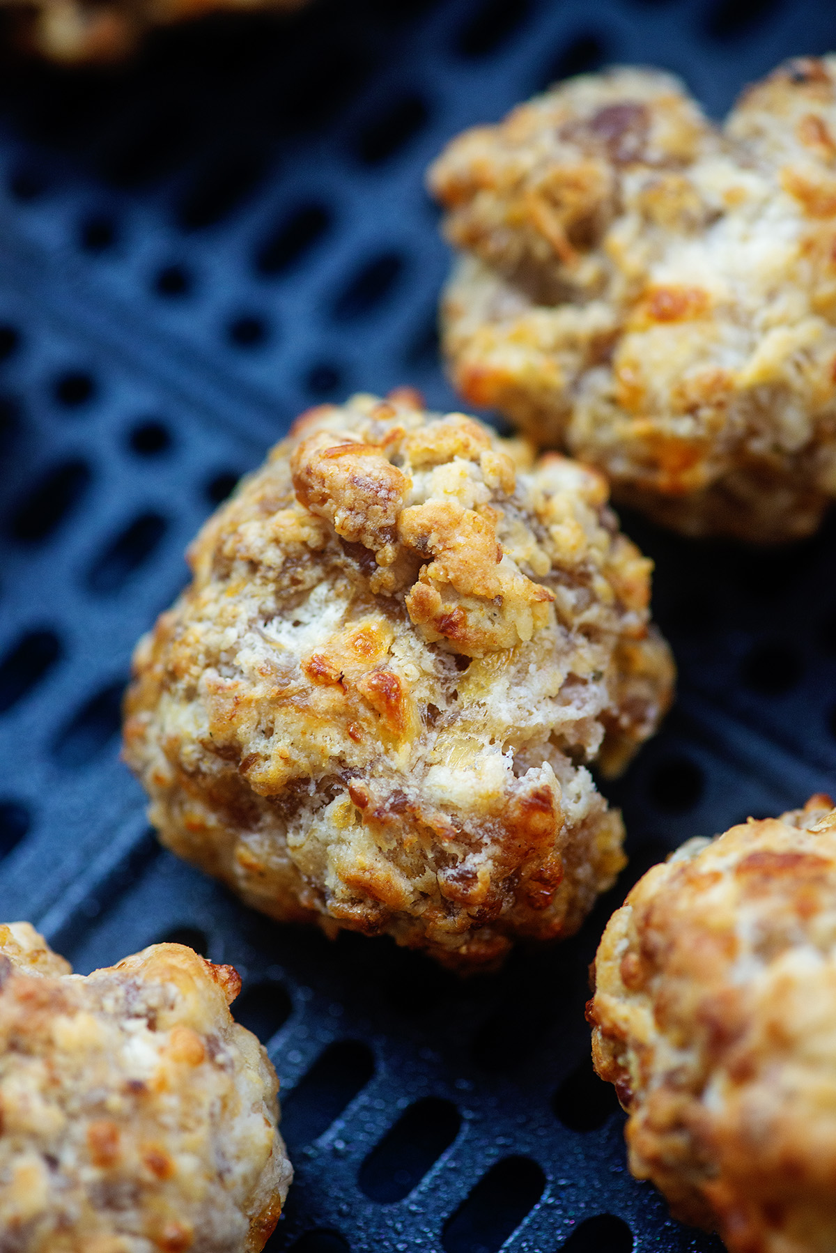 Close up of two sausage balls in an air fryer basket
