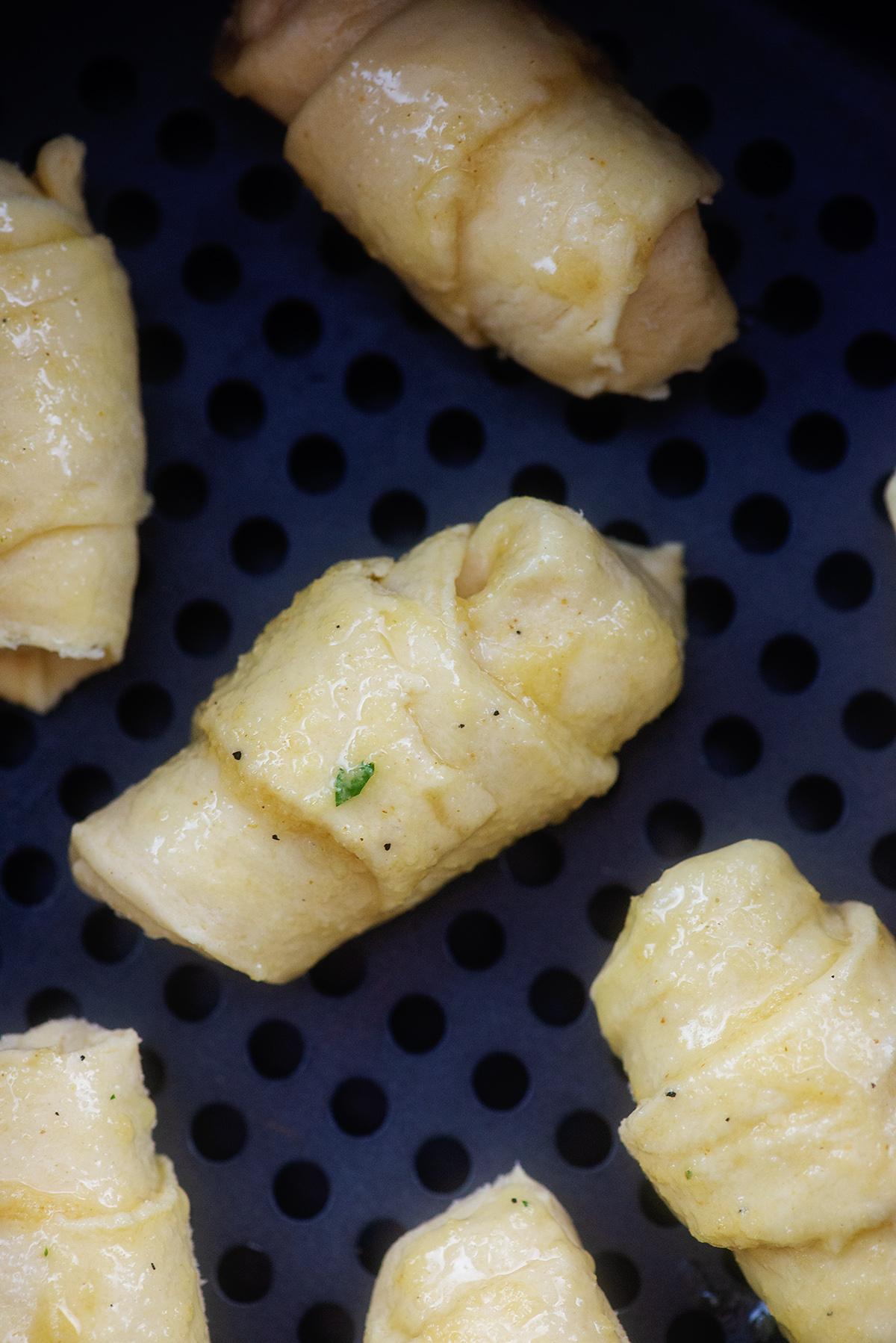 crescent rolls brushed with garlic butter in air fryer basket.