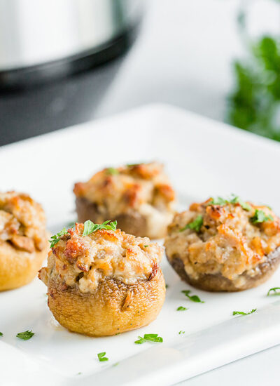 Close up of four stuffed mushrooms on a square white plate