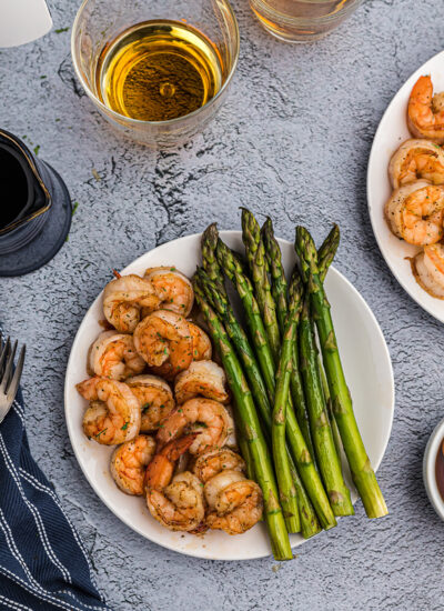 Overhead picture of a white plate with bourbon shrimp and asparagus on it.