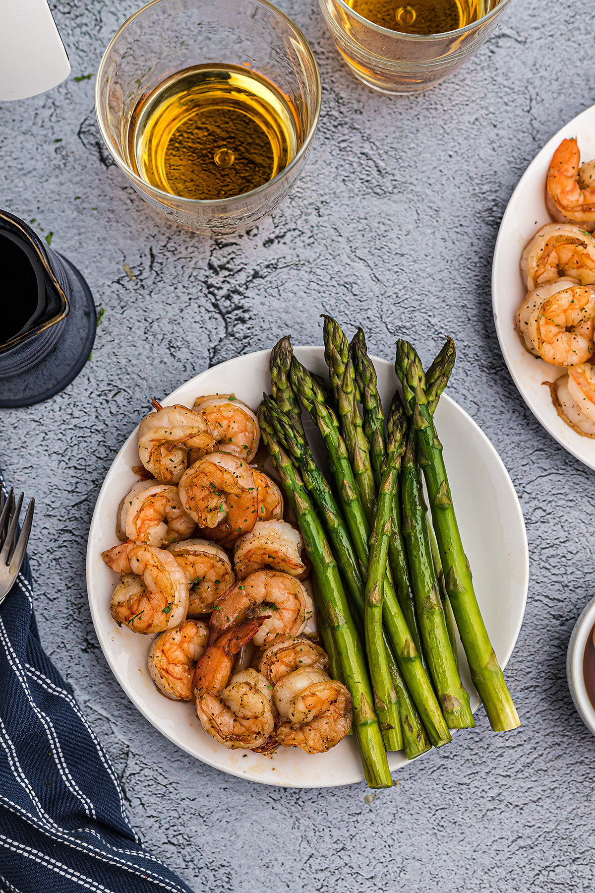 Overhead picture of a white plate with bourbon shrimp and asparagus on it.