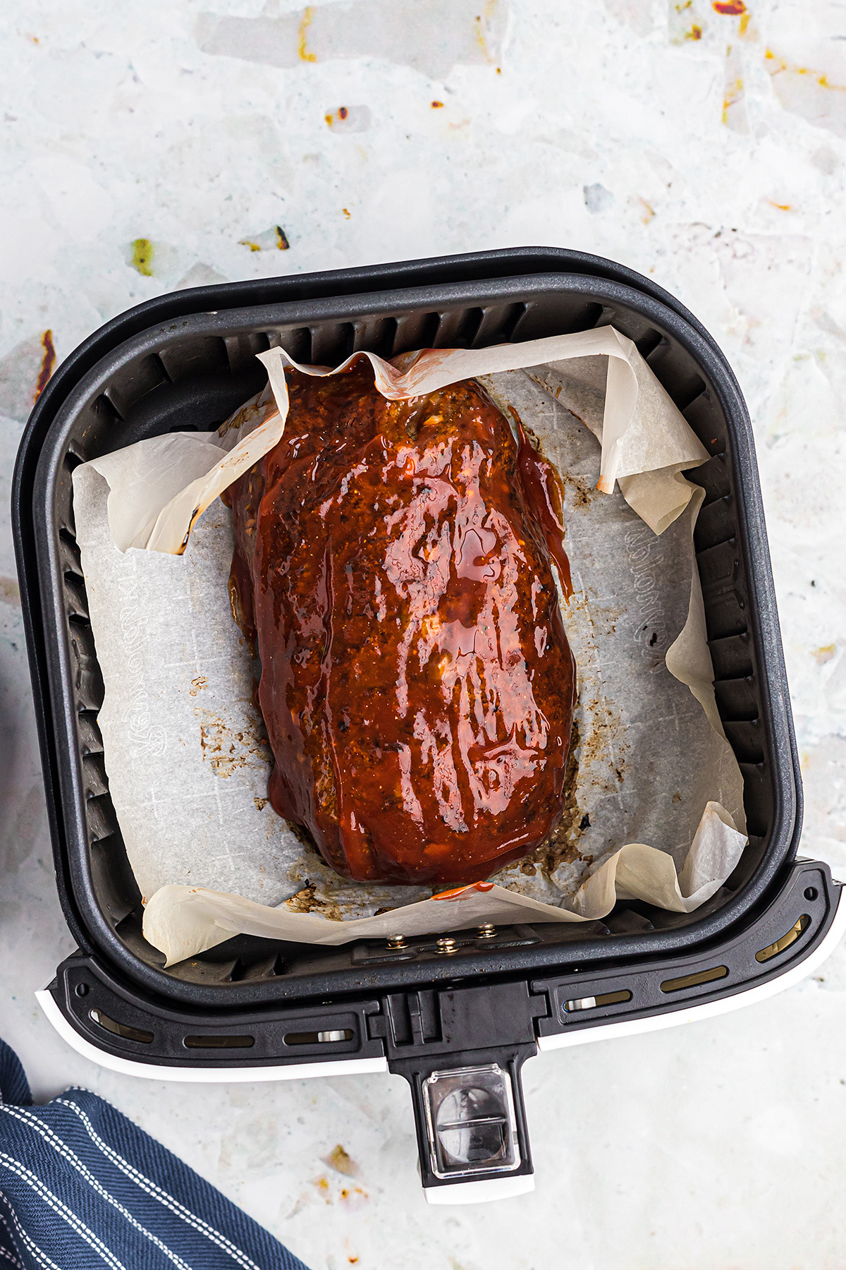 Overhead view of a glazed meatloaf in an air fryer basket.