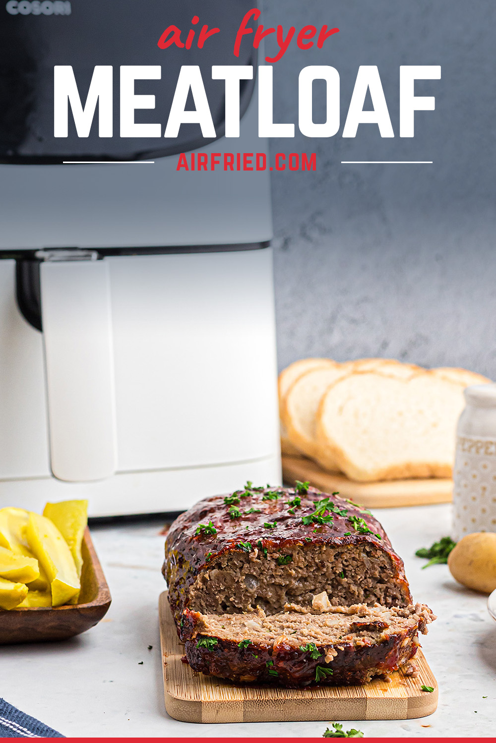 A meatloaf in front of an air fryer with a slice cut out of it.
