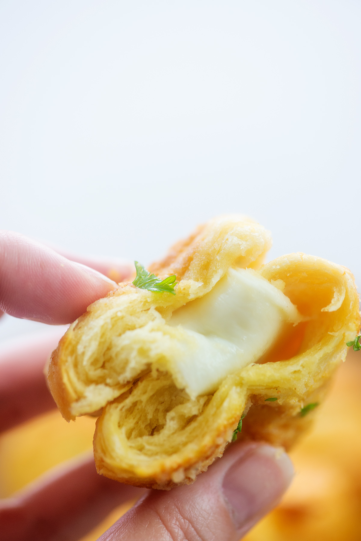 hand holding cheesy filled crescent roll.