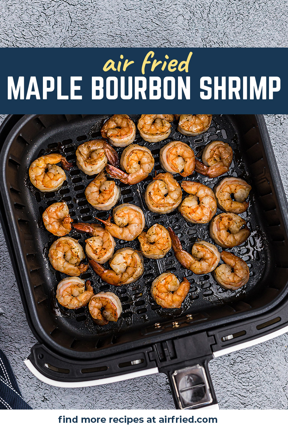 Cooked shrimp spread out in an air fryer basket with a maple bourbon glaze.