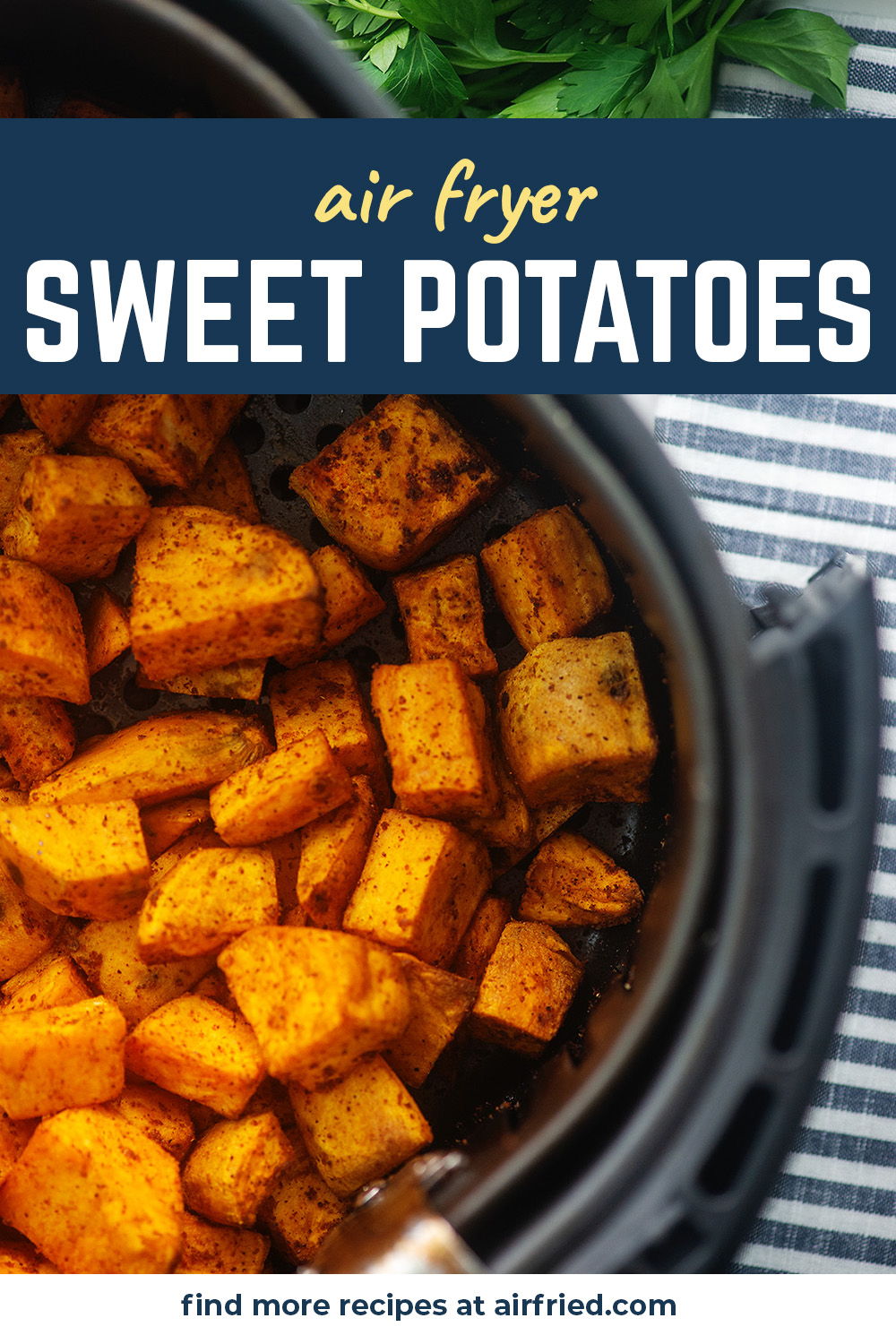Overhead view of sweet potato cubes in an air fryer basket on a striped cloth napkin.