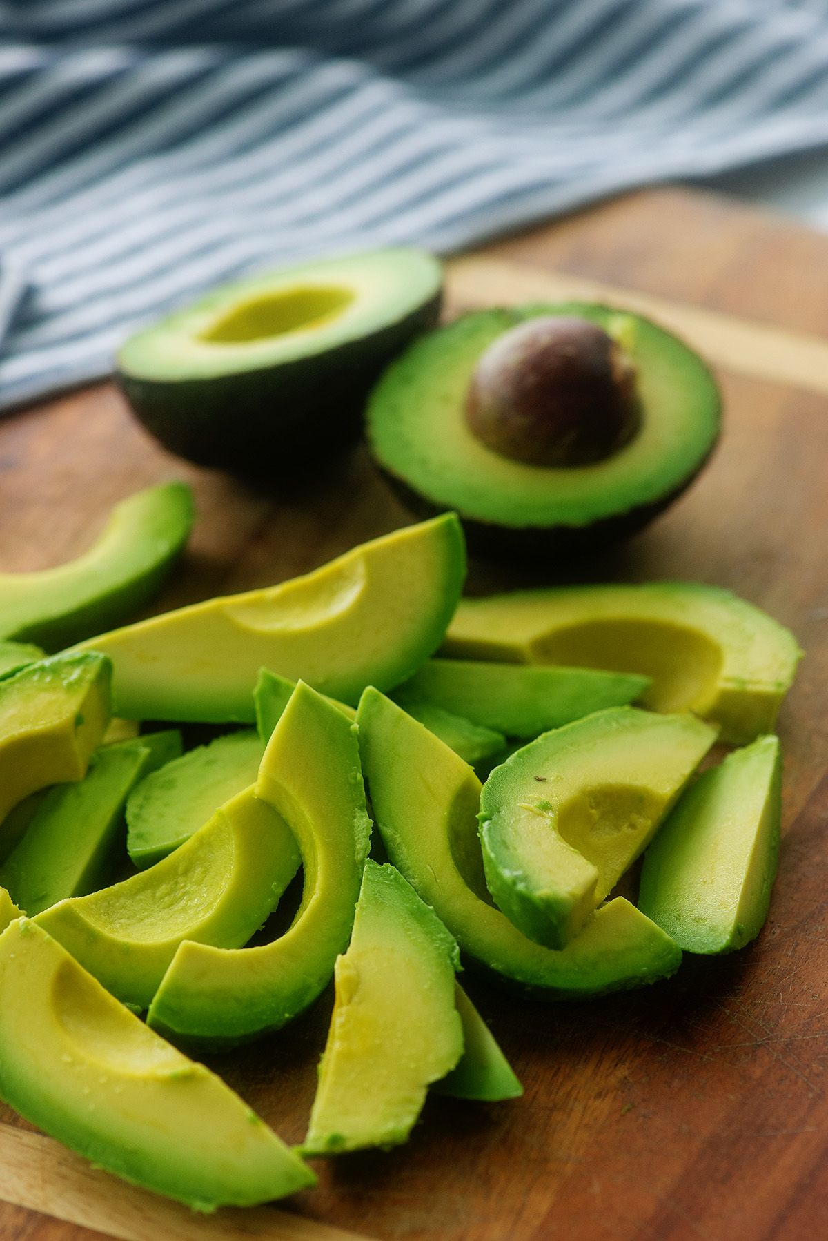Avocados cut into wedges on a cutting board.