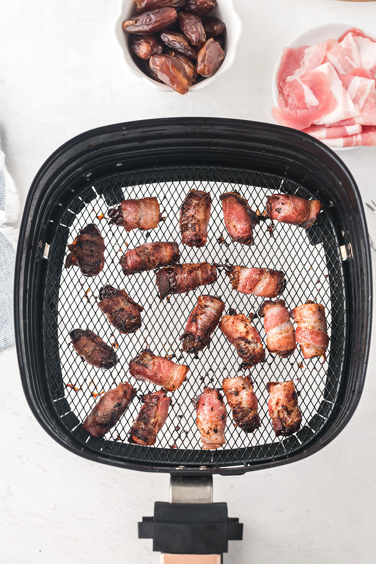 cooked bacon wrapped dates in an air fryer basket