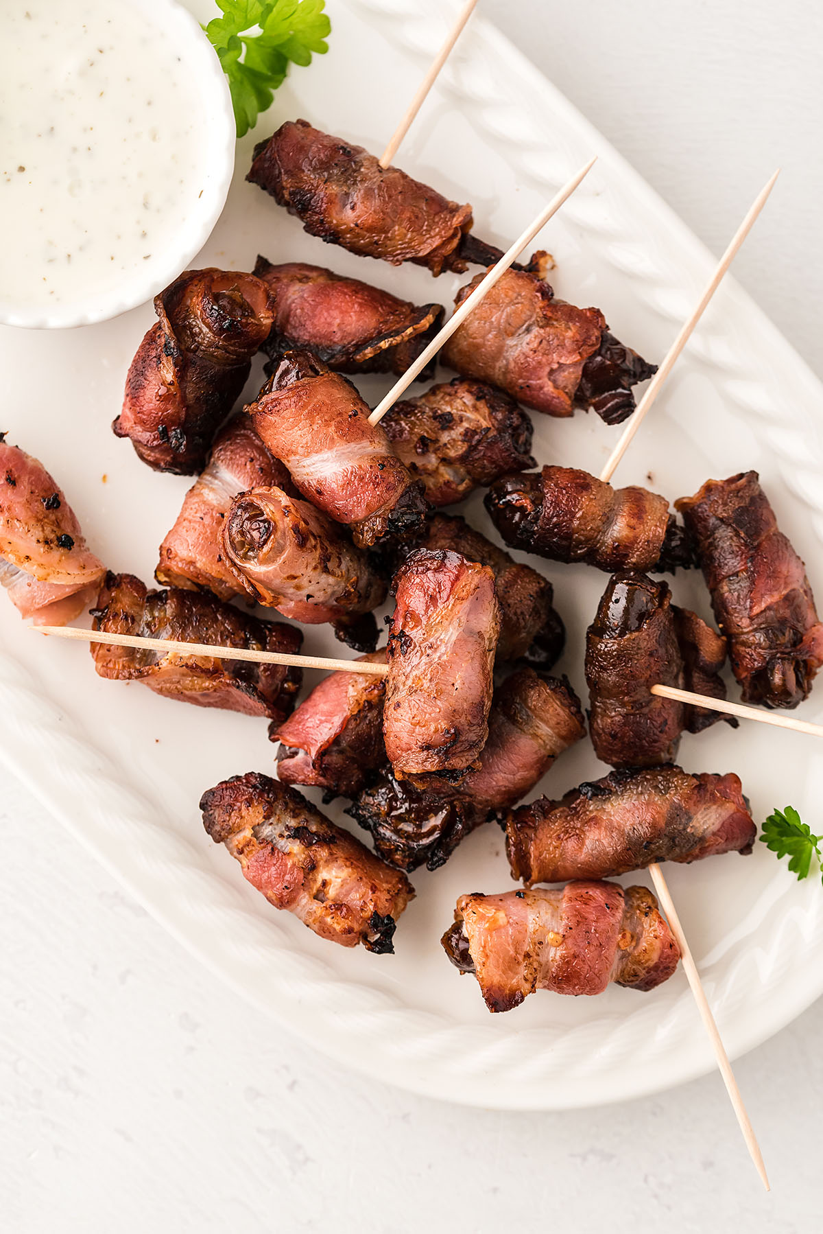 overhead view of bacon wrapped dates on a white serving tray