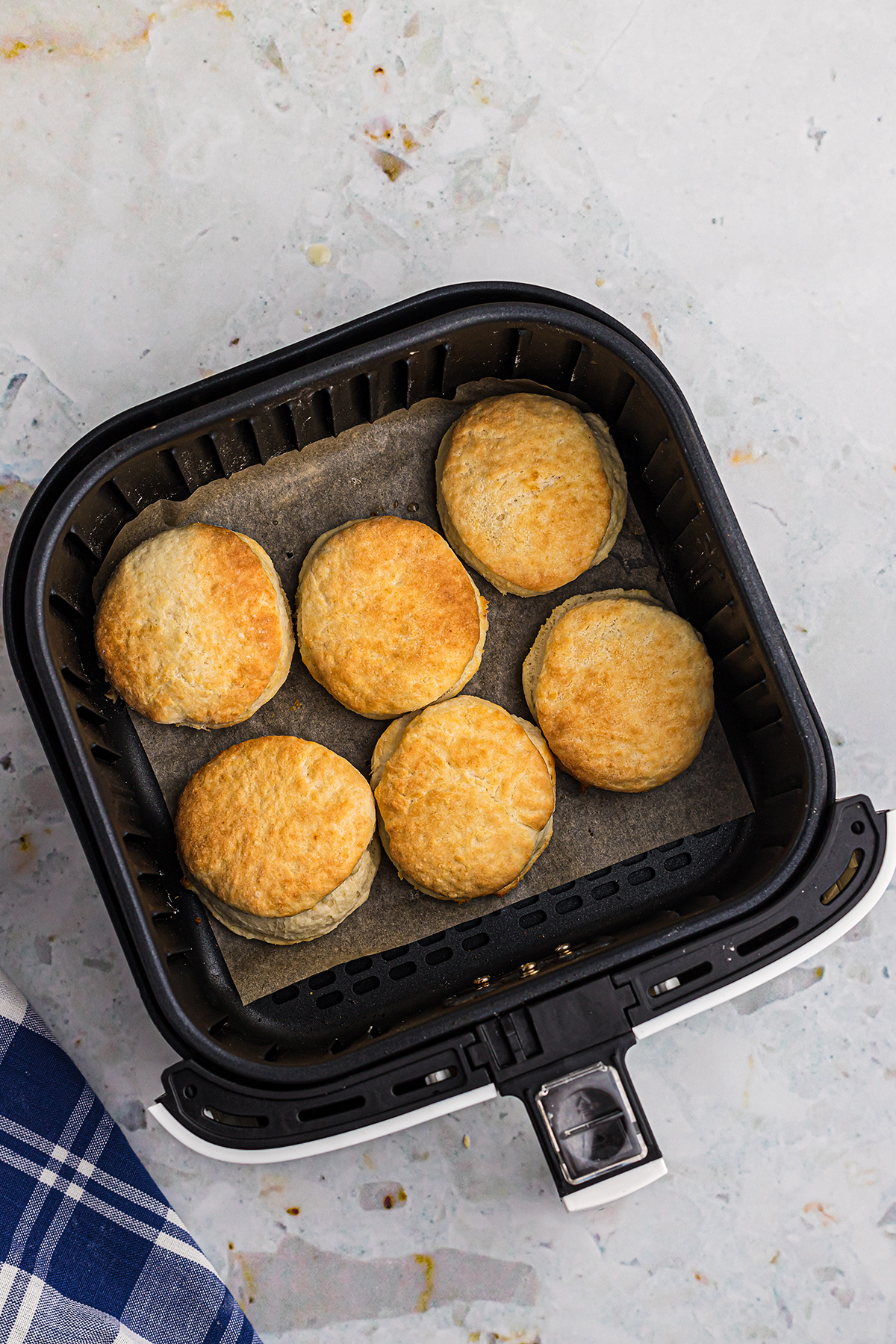Overhead view of biscuits in an air fryer basket.