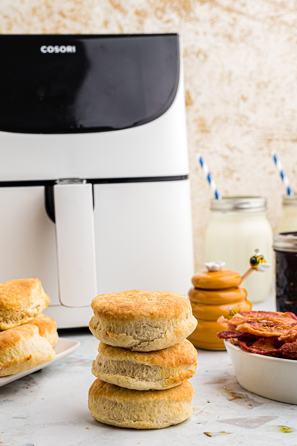 Biscuits stacked up in front of an air fryer.