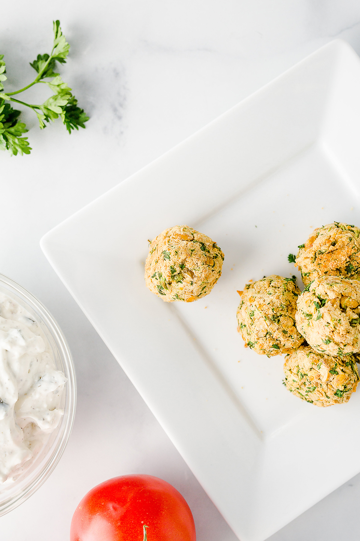 falafel balls piled on a square white plate