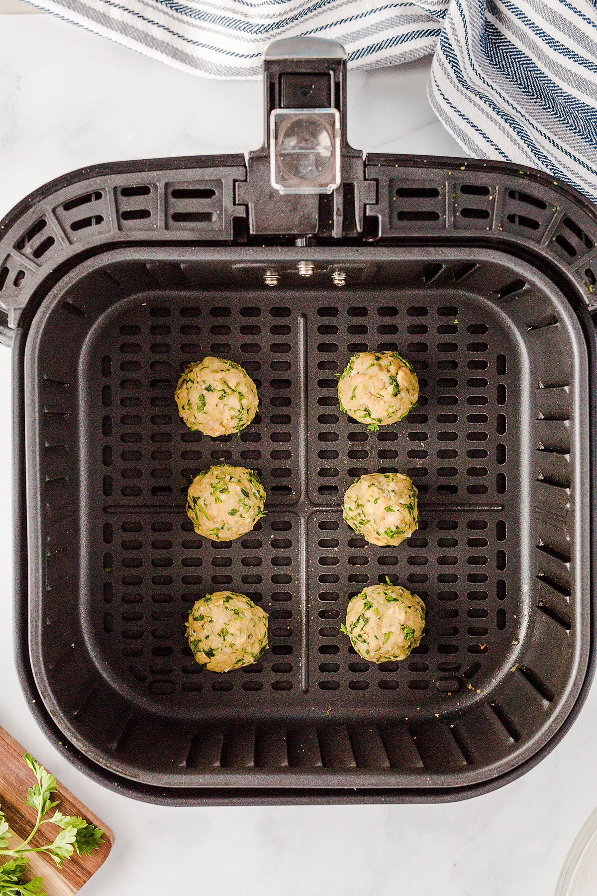 falafel balls spread out in an air fryer basket