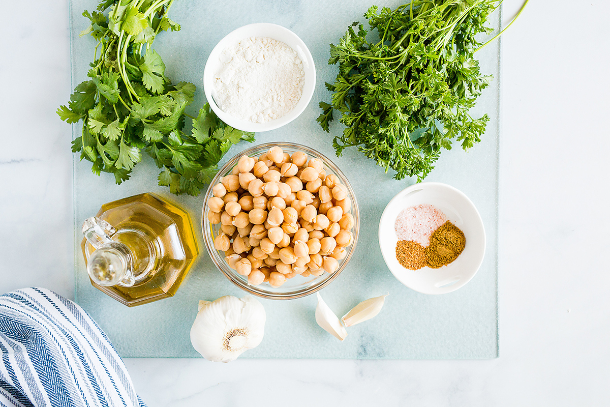 overhead view of a bowl of chickpeas next to other falafel ingredients