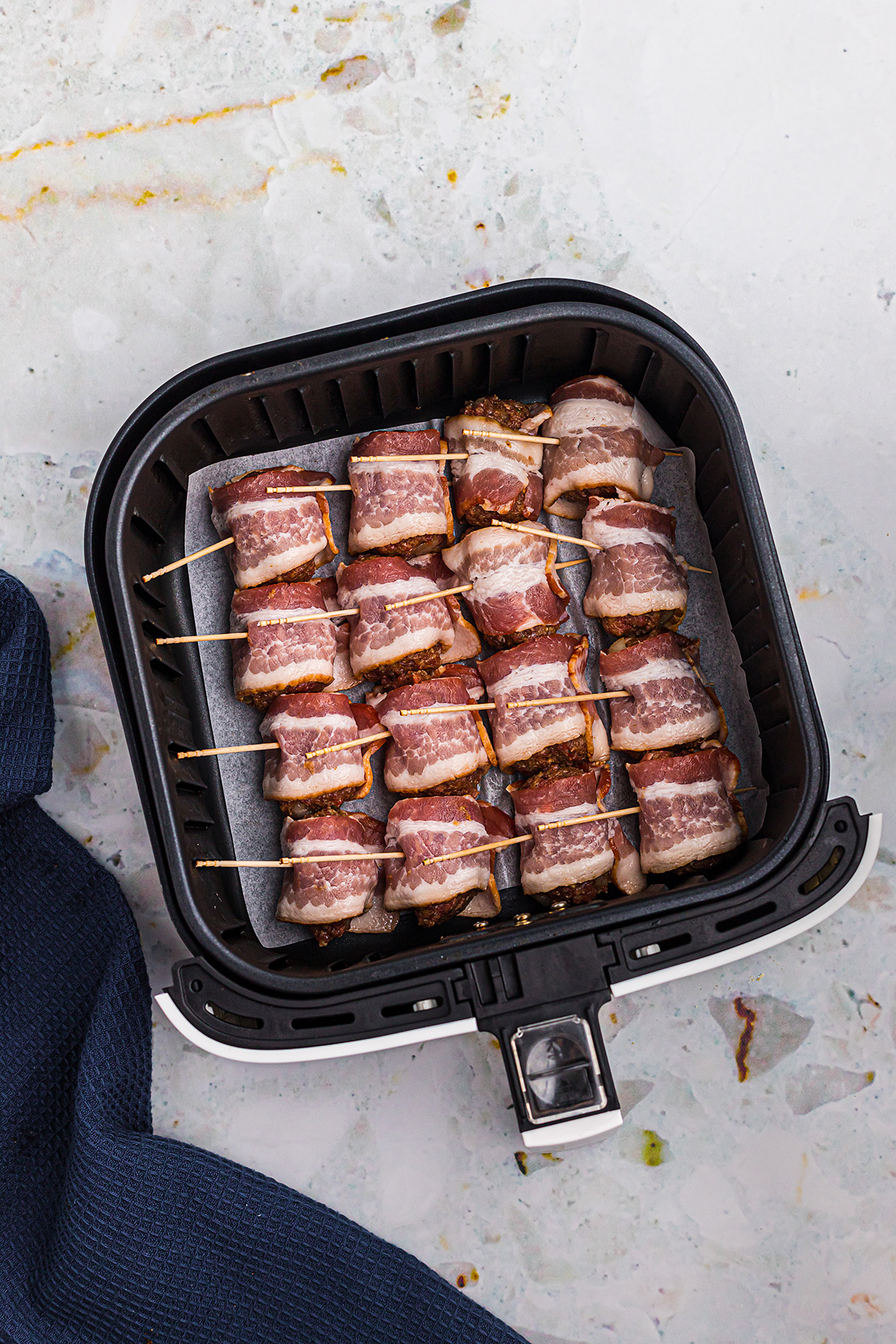 bacon wrapped meatballs in air fryer basket.