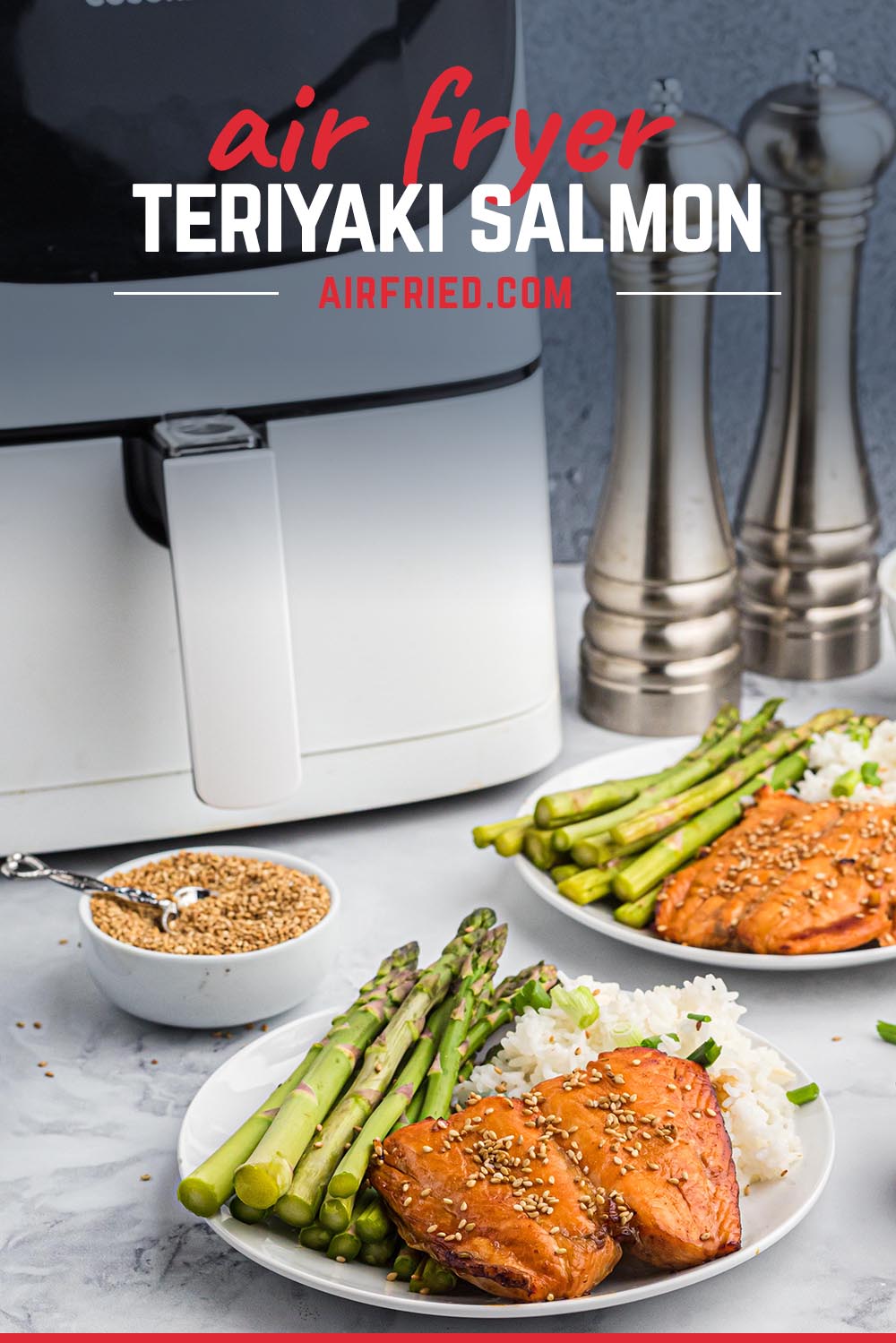A dinner plate with salmon and asparagus in front of an air fryer.