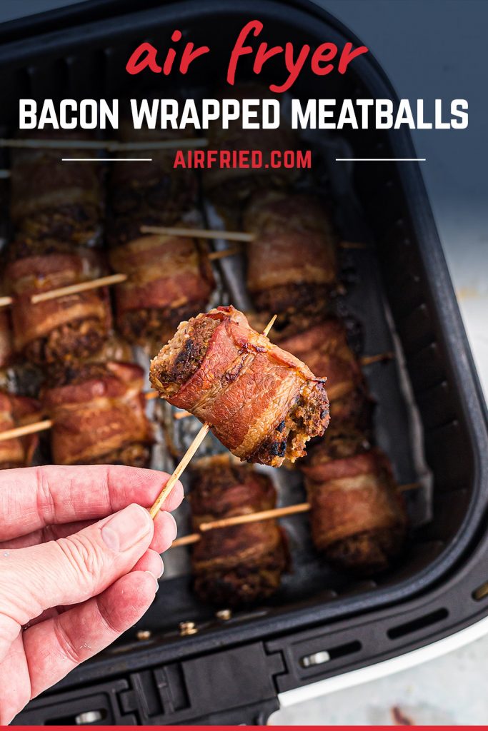 woman holding a bacon wrapped meatball over an air fryer basket.